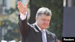 Ukraine's new president Petro Poroshenko (R) waves as he attends a flag raising ceremony after his inauguration in Kiev June 7, 2014. Poroshenko took the oath on Saturday as Ukraine's president, buoyed by Western support but facing an immediate crisis in
