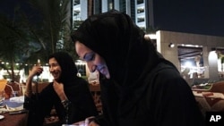 Saudi woman with cellphones smoke tobacco from a waterpipe as they drink coffee in Jeddah, Saudi Arabia, Nov. 2010 (file photo).