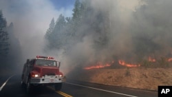 A fire truck drives past burning trees as firefighters continue to battle the Rim Fire near Yosemite National Park, California, Aug. 26, 2013