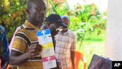 In this photo taken Oct 16, 2018, a man demonstrates using an electronic voting machine that will be used later in the year for the next election in Beni, Eastern Congo. 
