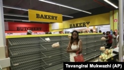 A woman walks past almost empty bread shelves in a shop in Harare, Tuesday, Oct, 9, 2018