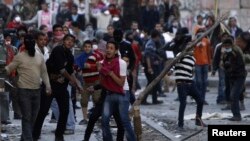 Anti-Morsi protesters throw stones towards riot police during clashes in Simon Bolivar Square, which leads to Tahrir Square, in Cairo, Egypt, January 30, 2013.