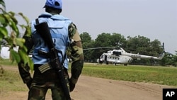 An U.N. peacekeeper in Ivory Coast stands guard by an UN helicopter used to transport officials and journalists from UNOCI headquarters to the Hotel du Golf, the temporary headquarters of Alassane Ouattara, in Abidjan, 3 Jan 2011