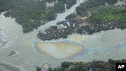 FILE - Oil is seen on the creek water's surface near an illegal oil refinery in Ogoniland, outside Port Harcourt, in Nigeria's Delta region, Mar. 24, 2011.