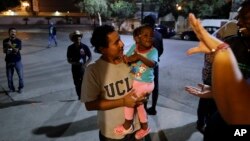 Guatemalan Elvin Vazquez (center) holds a Haitian girl immigrating with her family at a migrant shelter in Tijuana, Mexico, Nov. 14, 2016. Thousands of Haitians have arrived at the U.S. border with Mexico in recent months, many after traveling 7,000 miles through eight nations.