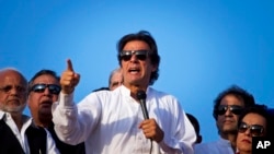 FILE - Pakistan's cricketer-turned-politician Imran Khan, center, is surrounded by aides as he addresses to his supporters near the parliament building in Islamabad, Pakistan, Aug. 27, 2014. 