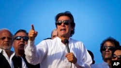 Pakistan's cricketer-turned-politician Imran Khan, center, is surrounded by aides as he addresses supporters near the parliament building in Islamabad, Aug. 27, 2014.