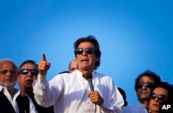 FILE - Pakistan's cricketer-turned-politician Imran Khan, center, is surrounded by aides as he addresses to his supporters near the parliament building in Islamabad, Pakistan, Aug. 27, 2014.