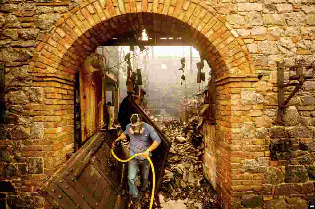 Cellar worker Jose Juan Perez extinguishes hotspots at Castello di Amorosa, Sept. 28, 2020, in Calistoga, California, which was damaged in the Glass Fire.
