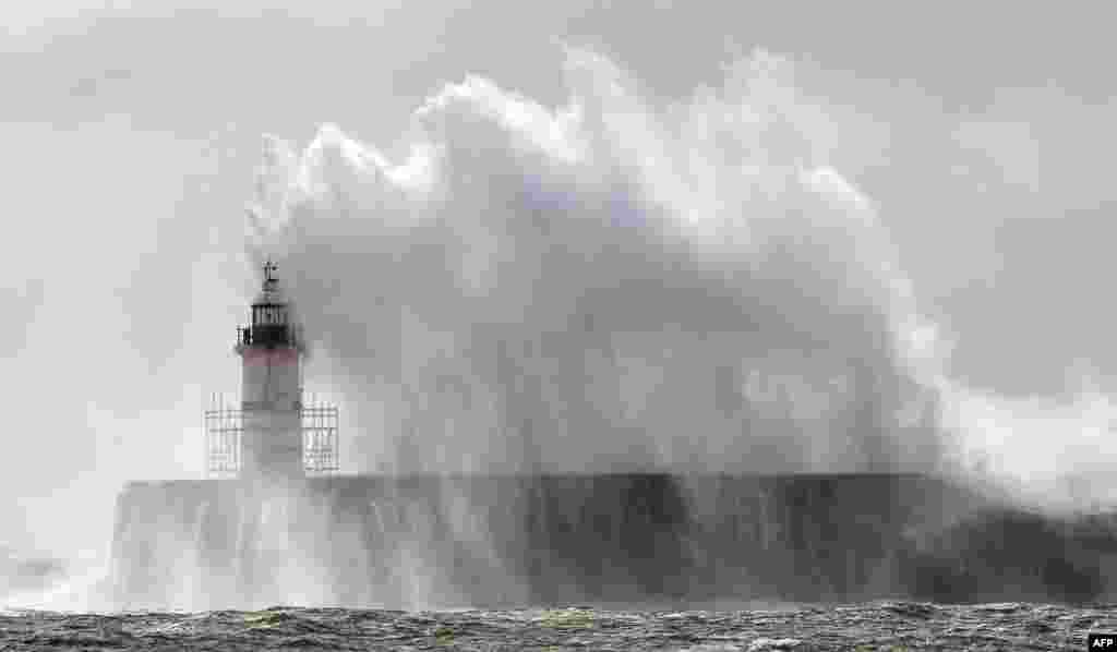 Waves crash into the harbor wall and over the lighthouse during high winds at Newhaven on the south coast of England.