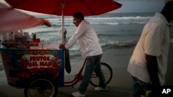 A vendor of seafood cocktails pushes his cart along the shore in Cartagena, Colombia, Tuesday. Colombia's government and the Revolutionary Armed Forces of Colombia, FARC, signed on Monday a peace agreement to end over 50 years of conflict.