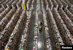 A worker gathers items for delivery from the warehouse floor at Amazon's distribution center in Phoenix, Arizona, Nov. 22, 2013.