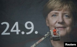 A crane operator steers his mobile crane next to a 18 meters wide 'Mega Poster' of Angela Merkel, German Chancellor and leader of the Christian Democratic Union party CDU after fixing the lights for Merkel's campaign picture.