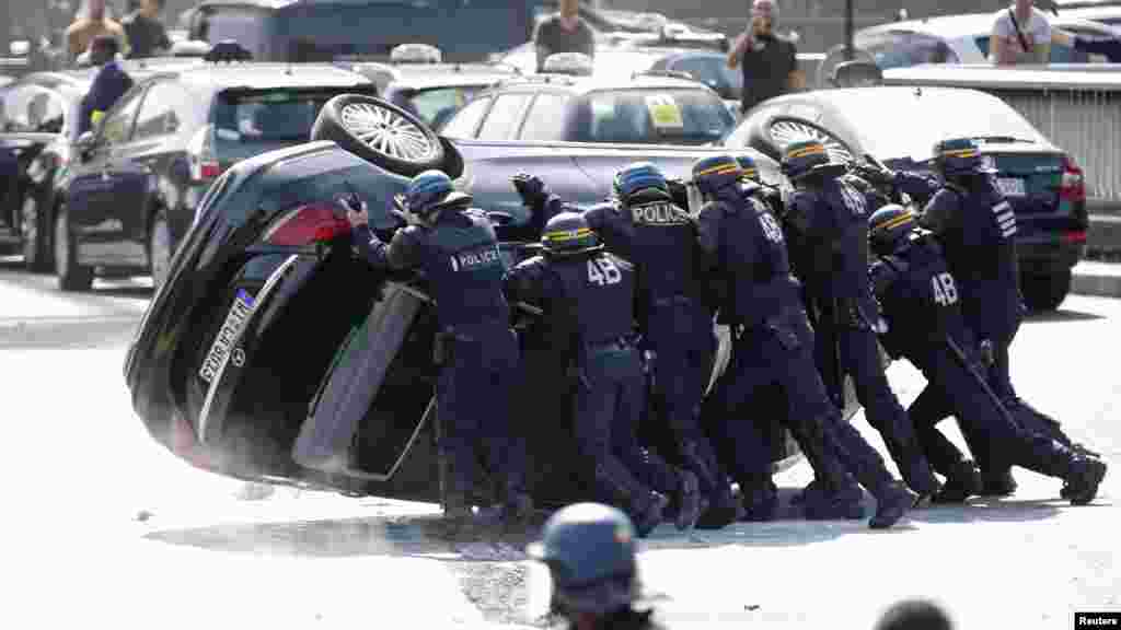 La police anti-émeutes françaises poussent une voiture renversée par des chauffeurs de taxi français qui manifestent Paris contre le groupe américain Uber à Porte Maillot pour bloquer le trafic à la périphérique de Paris, France, le 25 juin 2015