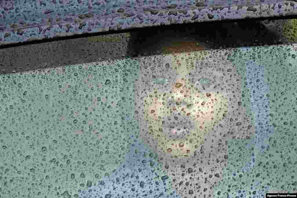 A child looks through the windshield of a car during a heavy rain shower in Chennai, India.