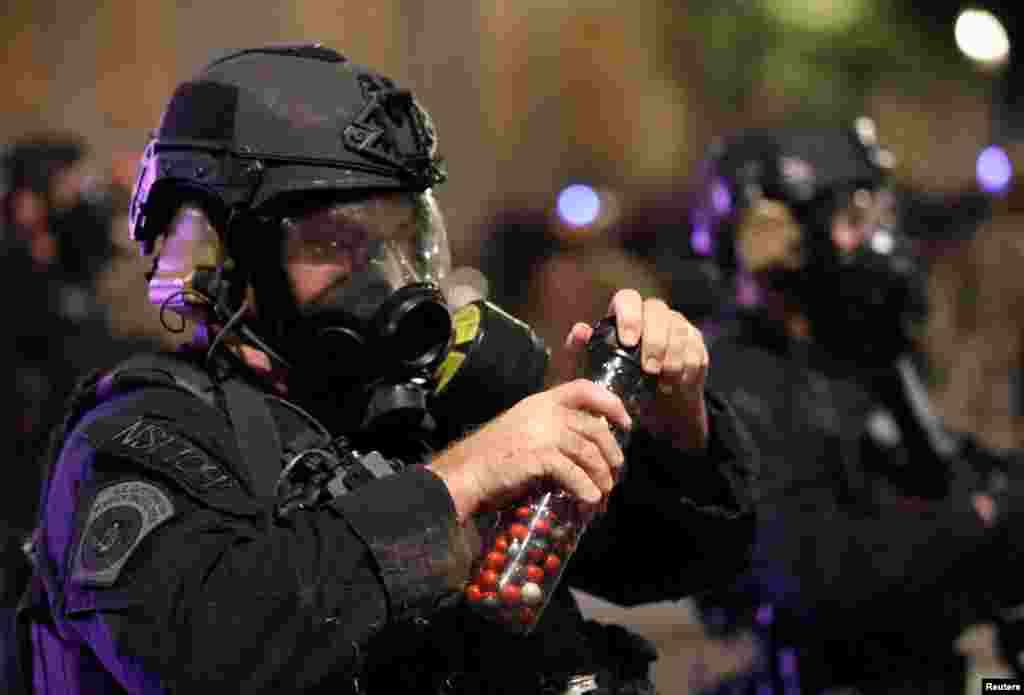 A federal law enforcement officer holds pepper balls during a protest against racial inequality and police violence in Portland, Oregon, July 28, 2020.