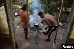 Venezuelans Hildemaro Ortiz and Ixora Sanguino cook outside of an abandoned bus in the border city of Pacaraima, Brazil, April 13, 2019.