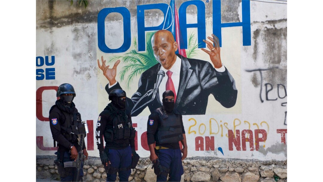 Polisi berdiri di dekat mural yang menampilkan Presiden Haiti Jovenel Moise, di dekat kediaman pemimpin tempat dia dibunuh oleh orang-orang bersenjata pada dini hari di Port-au-Prince, Haiti, Rabu, 7 Juli 2021. (Foto: AP/Joseph Odelyn)