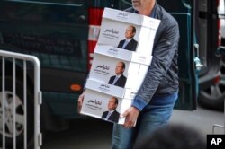 FILE - Workers in Cairo carry boxes that bear Egyptian President Abdel-Fattah el-Sissi’s image and the phrase “Long live Egypt!” in this undated image released Jan. 24, 2018, on the official Facebook account of the president.