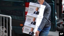 This undated image released Jan. 24, 2018 on the official Facebook account of Egyptian President Abdel-Fattah el-Sissi, shows workers carrying boxes that bear the president’s image and the phrase “long live Egypt!” in Cairo Egypt. The boxes contained “recommendations” from voters who want him to run again. 