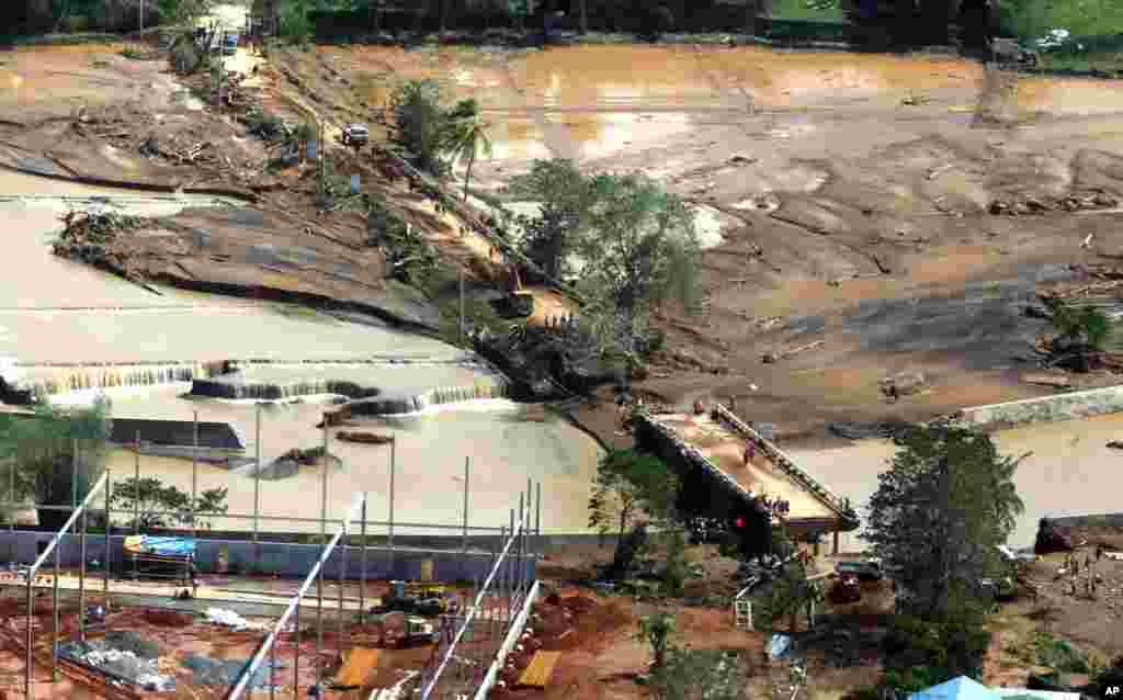 In this photo provided by Malacanang Presidential Photographers Division, residents try to make their way on the damaged Caraycaray Bridge after Tropical Storm Kai-Tak hit the island province of Biliran, central Philippines.