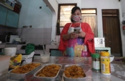 Rani Nurwitawati checks her mobile phone as she prepares food for her online customers at her residence in Bekasi on the outskirts of Jakarta, Indonesia, Nov. 26, 2020.