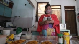 Rani Nurwitawati checks her mobile phone as she prepares food for her online customers at her residence in Bekasi on the outskirts of Jakarta, Indonesia, Nov. 26, 2020.