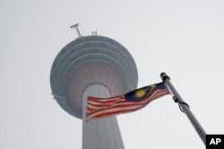 Bendera Malaysia berkibar di bawa Menara KL di Kuala Lumpur, Malaysia, yang diselimuti kabut asap kebakaran hutan di Indonesia, 18 September, 2019. (Foto: Vincent Thian/AP Photo)