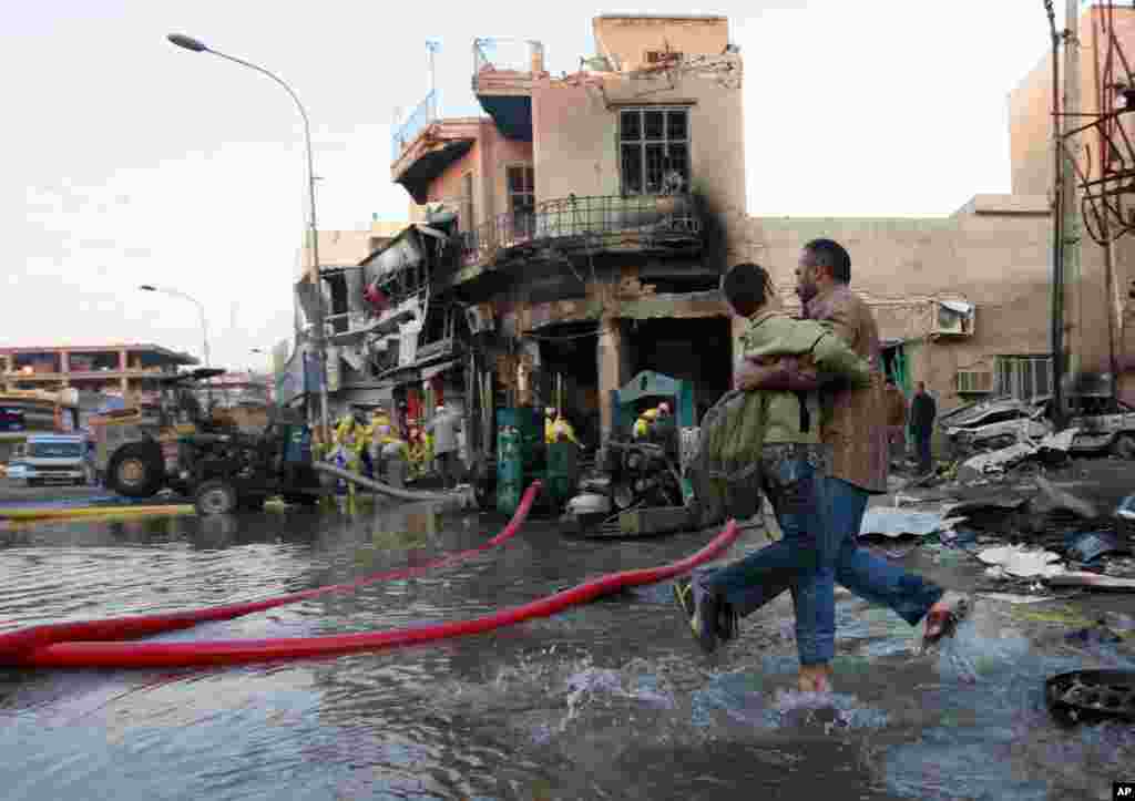 Sambil berjalan melewati lokasi serangan bom mobil, seorang pria Irak membantu anaknya pergi ke sekolah,&nbsp;Baghdad, Irak, 18 Februari 2014.&nbsp;