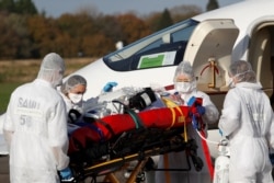 Medical staff members move a patient from a plane during a transfer operation of people suffering from the coronavirus disease (COVID-19), at Vannes Airport, France, Nov. 2, 2020.