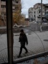FILE - A photographer walks past buildings damaged by a Russian military strike, in the town of Pokrovsk in Donetsk region, Ukraine, Nov. 4, 2024. 