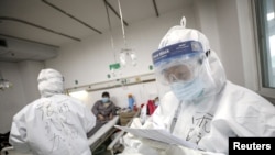 A medical worker in protective suit checks a patient's records at Jinyintan hospital in Wuhan, the epicenter of the novel coronavirus outbreak, in Hubei province, China, Feb. 13, 2020.