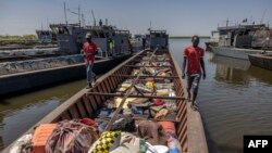 FILE —People walk on a boat loaded with belongings from families who have fled the war in Sudan at the shores of the White Nile River in the Port of Renk on February 14, 2024.