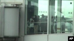 Chinese activist Chen Guangcheng, left, is pushed in a wheelchair at Beijing International airport Saturday May 19, 2012.