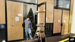 A worker cleans up damage to a bank, Dec. 8, 2014, the result of a violent protest Sunday night in Berkeley, California.