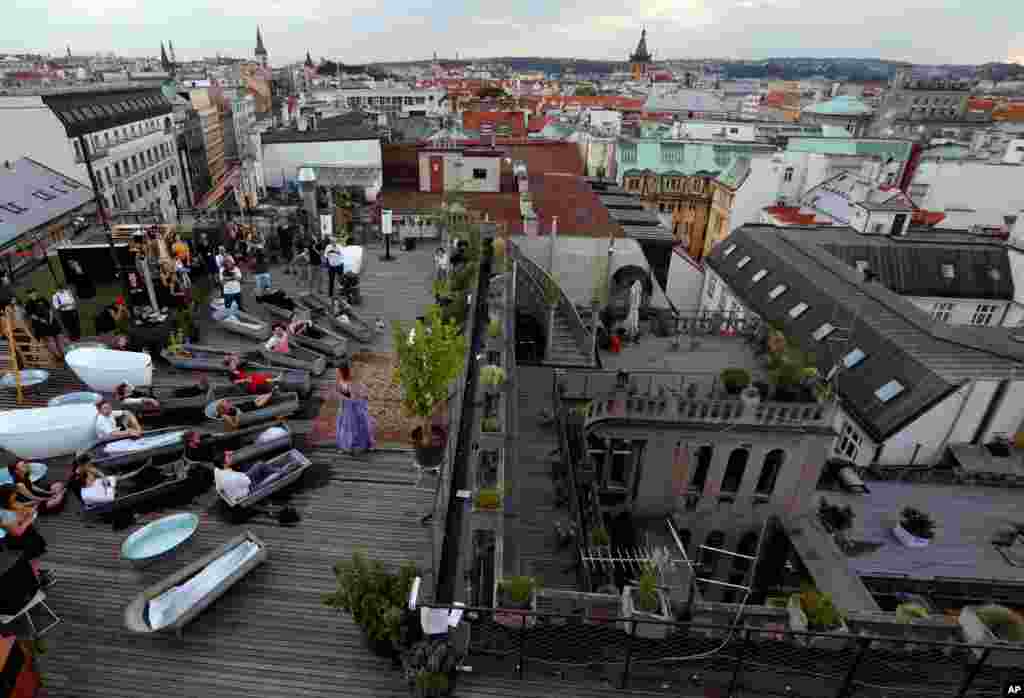 Spectators soak in bathtubs while listening to Czech opera singer Eva Kyvalova performing parts of Mozart&#39;s Don Giovanni at the rooftop of Lucerna building in Prague, Czech Republic.