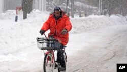 Terrence Yarbrough, de Erie, Pensilvania, viaja en su bici por las calles cubiertas de nieve, en el centro de Erie, el 2 de diciembre de 2024. (AP Foto/Gene J. Puskar).