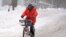 Terrence Yarbrough, de Erie, Pensilvania, viaja en su bici por las calles cubiertas de nieve, en el centro de Erie, el 2 de diciembre de 2024. (AP Foto/Gene J. Puskar).