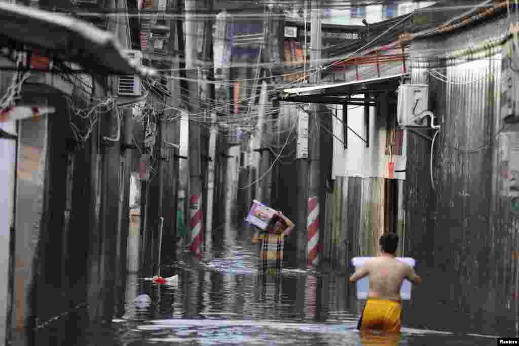 2018年9月2日，中国广东省汕头市一个镇遭遇暴雨，男子携带财物穿过住宅旁边的洪水（2018年9月2日）。