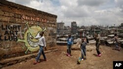 FILE - Children walk past graffiti depicting a representation of the coronavirus and warning people to sanitize to prevent its spread, in the Mathare slum of Nairobi, Kenya, April 22, 2020.