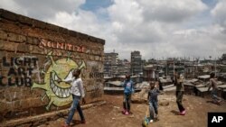 FILE - Children walk past graffiti depicting a representation of the coronavirus and warning people to sanitize to prevent its spread, in the Mathare slum of Nairobi, Kenya, April 22, 2020.