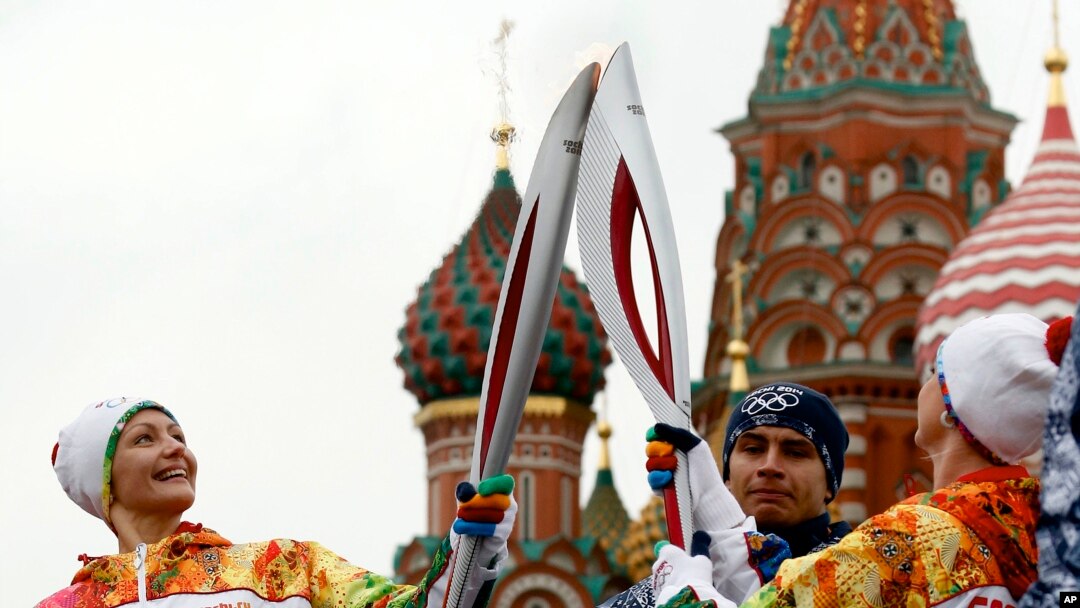 Russian Olympic gold medalists, synchronized swimmer Anastasya Davydova (L) and former artistic gymnast Svetlana Khorkina (R), join their torches during a relay of the Olympic flame in Moscow, Oct. 7, 2013. 