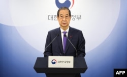 Perdana menteri dan penjabat Presiden Korea Selatan Han Duck-soo membacakan pidato di Kompleks Pemerintahan, di Seoul, Kamis, 26 Desember 2024, sehari sebelum dimakzulkan oleh Parlemen. (Foto: Yonhap/AFP)