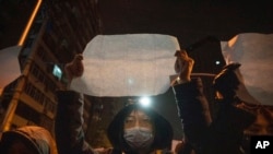 FILE: Protesters hold up blank pieces of paper and chant slogans as they march to protest strict anti-virus measures in Beijing, Nov. 27, 2022. 