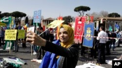 Yasmine Ouirhane berswafoto sambil menggengam bendera Uni Eropa dan bersiap-siap untuk ikut serta dalam unjuk rasa mendukung Uni Eropa di Roma, Sabtu, 25 Maret 2017 (foto: AP Photo/Gregorio Borgia)