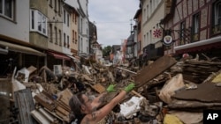 FILE - A woman throws away rubbish in the center of Bad Neuenahr-Ahrweiler, Germany, after heavy rainfall turned tiny streams into raging torrents across parts of western Germany and Belgium, July 19, 2021.