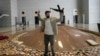 A man holds an AK-47 and flashes the victory sign as he poses for a photo in a hall of Syrian President Bashar Assad's presidential palace in Damascus, Dec. 8, 2024.