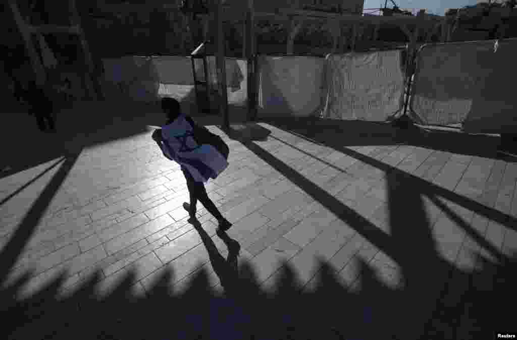 A visitor wrapped with Israel&#39;s national flag walks towards the Western Wall, Judaism&#39;s holiest prayer site, in Jerusalem&#39;s Old City.