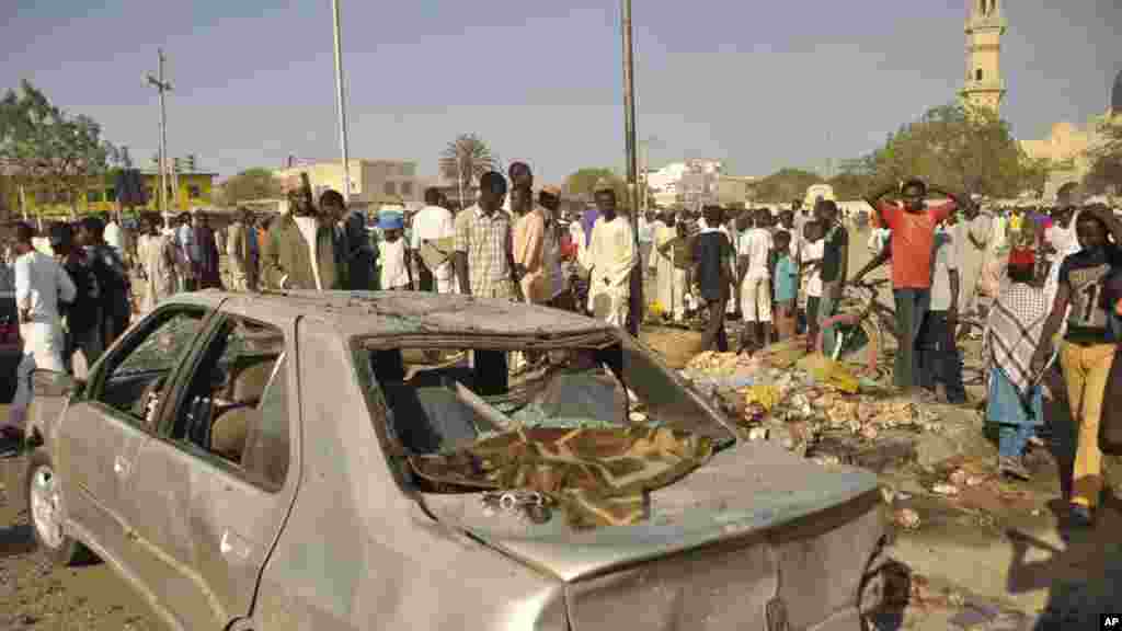 Mutane sun taru su na kallo a inda bam ya tashi a babban Masallacin Jumma&#39;a na Kano, Jumma&#39;a 28 Nuwamba, 2014. Mutane da yawa sun rasa rayukansu, kuma jami&#39;ai suka ce watakila yawan wadanda zasu hallaka zai karu.