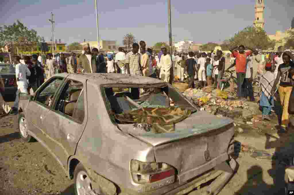 Mutane sun taru su na kallo a inda bam ya tashi a babban Masallacin Jumma&#39;a na Kano, Jumma&#39;a 28 Nuwamba, 2014. Mutane da yawa sun rasa rayukansu, kuma jami&#39;ai suka ce watakila yawan wadanda zasu hallaka zai karu.